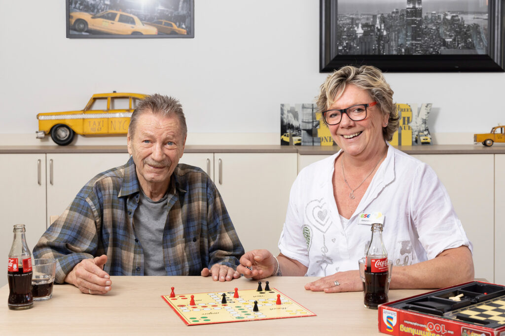 Ein Bewohner und eine Mitarbeiterin spielen das Spiel "Mensch ärgere Dich nicht".