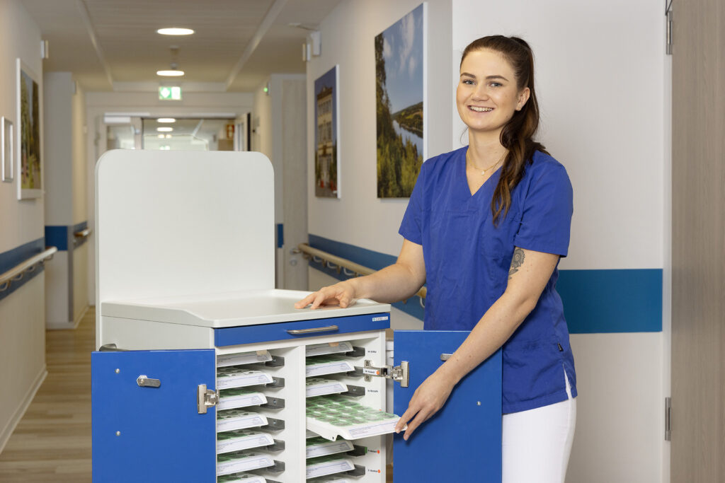 Eine Mitarbeiterin der Pflege lächelt in die Kamera.