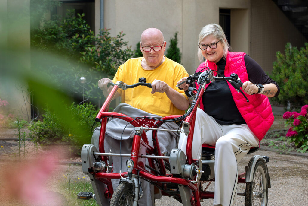 Mitarbeiterin und Bewohner machen einen gemeinsamen Ausflug mit dem Therapiefahrrad.