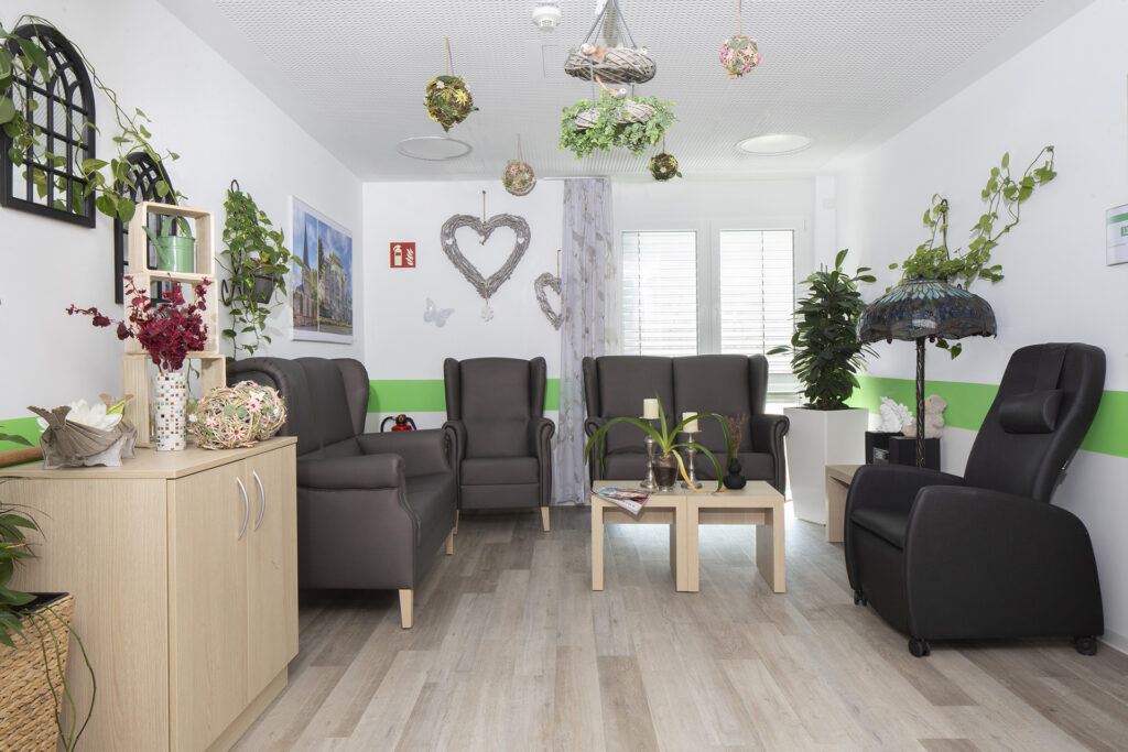 Blick in einen Aufenthaltsbereich: Eine gemütliche Sitzgruppe mit Sesseln, kleinen Tischen und Dekoration.