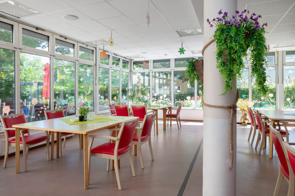 Blick in den Speiseraum, in den durch eine Fensterfront viel Licht fällt.