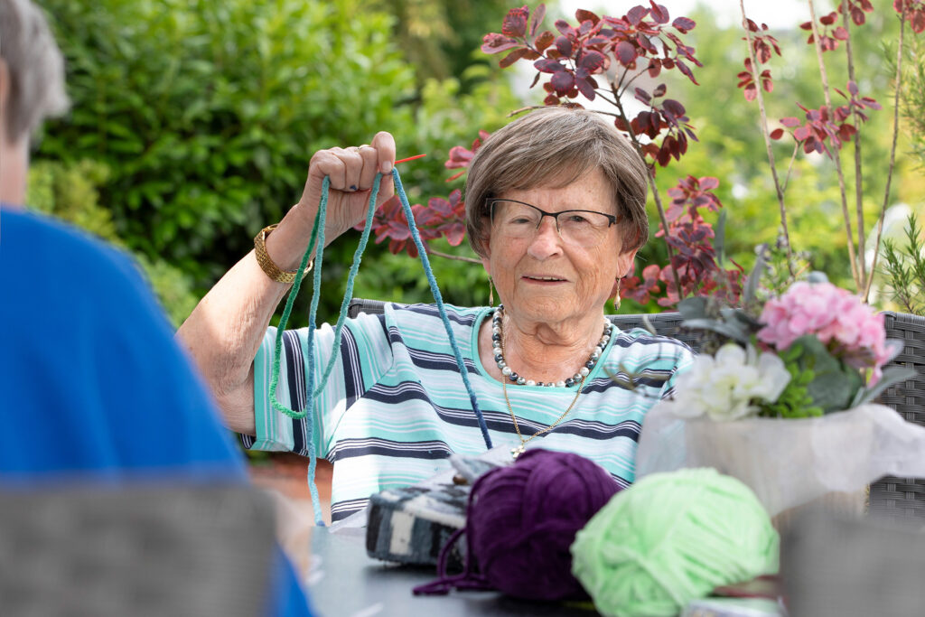 Eine Bewohnerin fertigt etwas in einer Handarbeitsrunde.