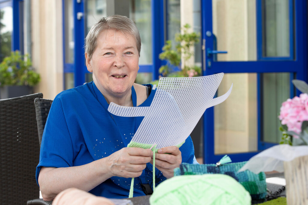 Eine Bewohnerin fertigt in der Handarbeitsgruppe ein Werkstück an.