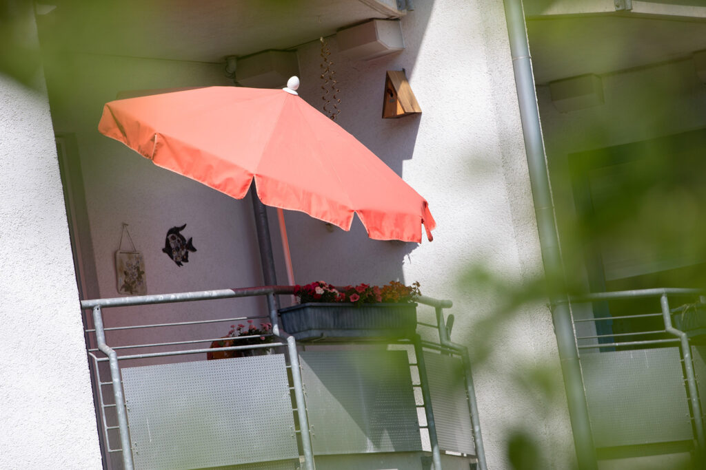 Blick auf einen Balkon der Wohnanlage Drostenbusch, auf dem ein Sonnenschirm aufgespannt ist.