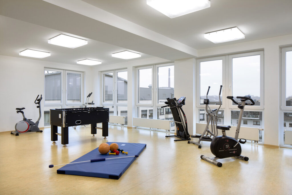Blick in den Fitnessraum: Neben Gymnastikmatte und kleinen Fitnessgeräten stehen auch Heimtrainer, Stepper und ein Kickertisch zur Verfügung.