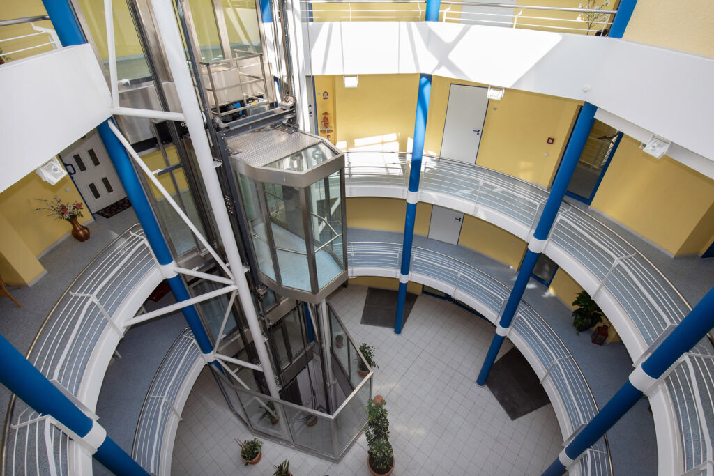Blick in das Treppenhaus: Alles ist geräumig. Ein gläserner Aufzug ermöglicht den barrierefreien Zugang zu jeder Etage.
