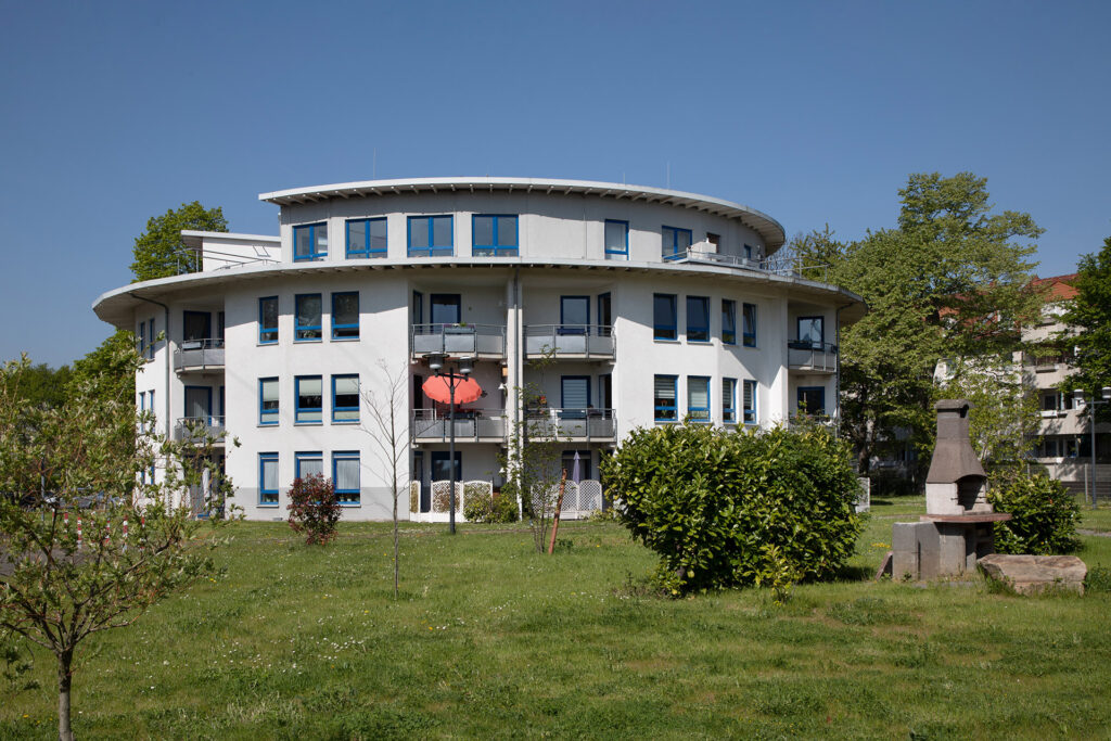 Blick von außen auf die Wohnanlage Drostenbusch: Die Rundbauten sind architektonisch attraktiv. Rund um die Wohnanlage ist ein großer Grünbereich.