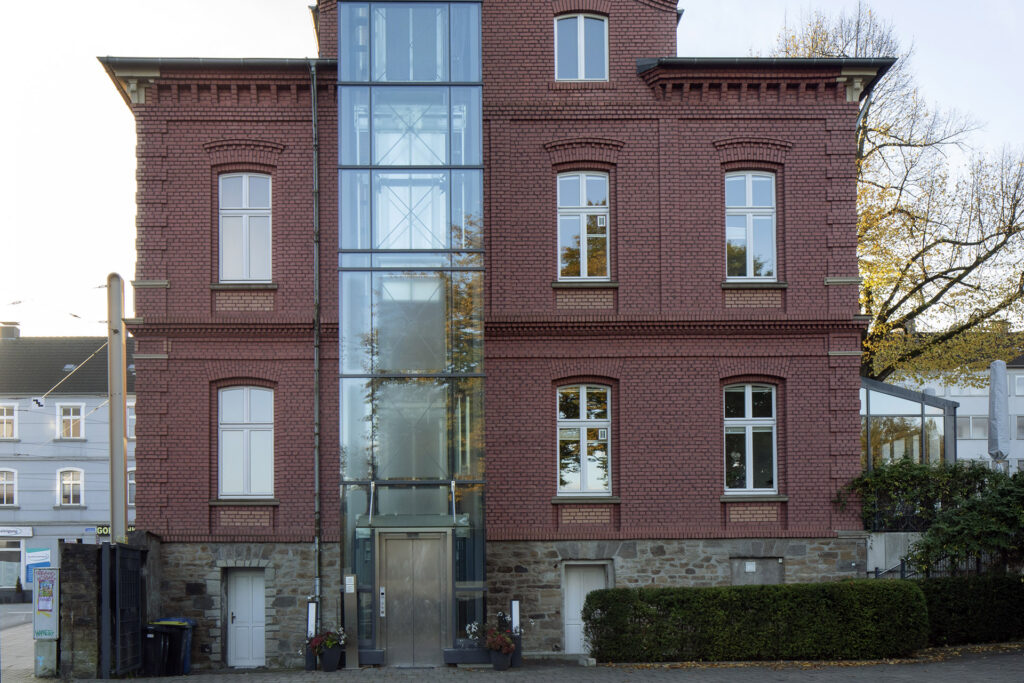 Blick auf die Rückseite der Tagespflege Rathaus Rellinghausen. Hier ist der Zugang zum verglasten Aufzug.