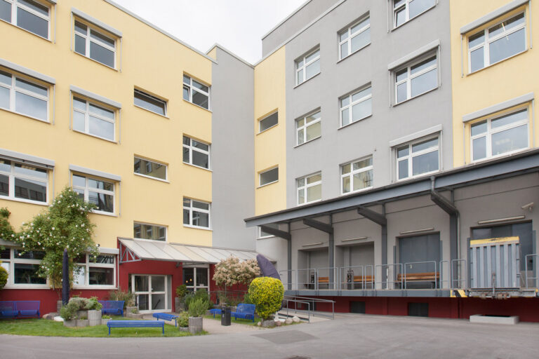 Blick auf den Innenhof der GSE-Werkstatt Holsterhausen mit Bepflanzung und der Anlieferungsrampe