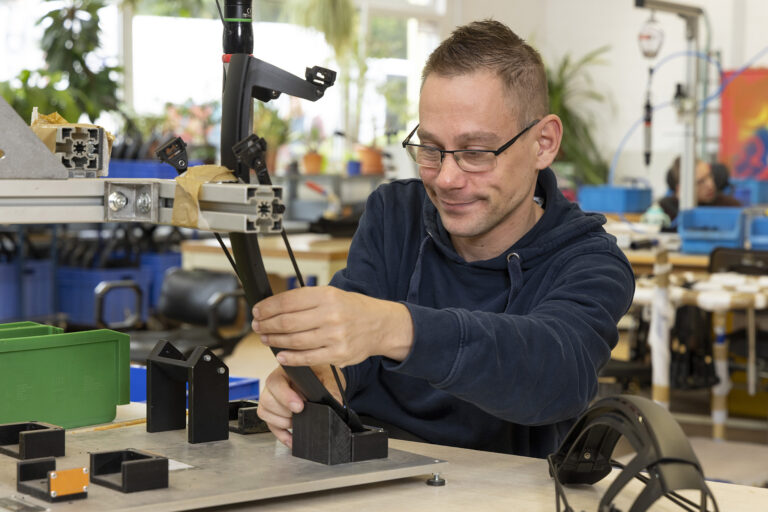 Ein Werkstattmitarbeiter baut konzentriert Fahrradteile zusammen.