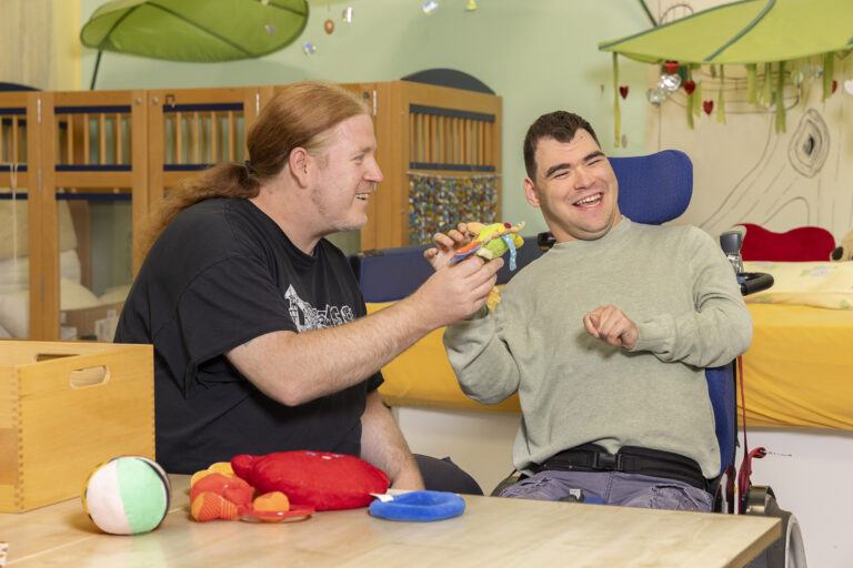 Ein GSE-Mitarbeiter reicht einem Werkstattmitarbeiter ein Stofftier an.