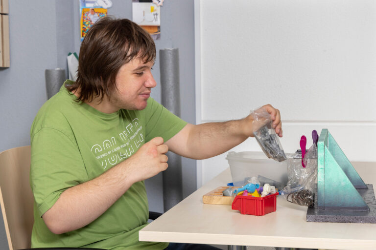 Ein Teilnehmer sortiert an einem Arbeitsplatz Luftballons.