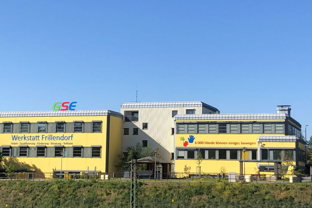 Das gelbe Gebäude der GSE-Werkstätten Frillendorf A, B und C ist zu sehen. Auf dem Dach ist ein großes GSE-Schild angebracht.