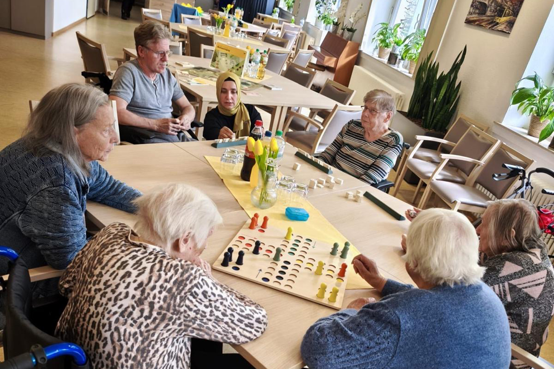 Mehrere Bewohner und Mitarbeitende spielen Gesellschaftsspiele.